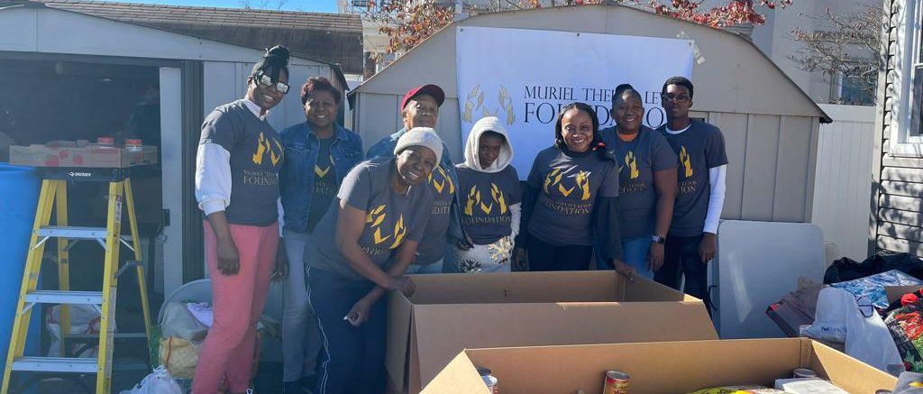 Picture of members of the foundation standing behind two boxes of food